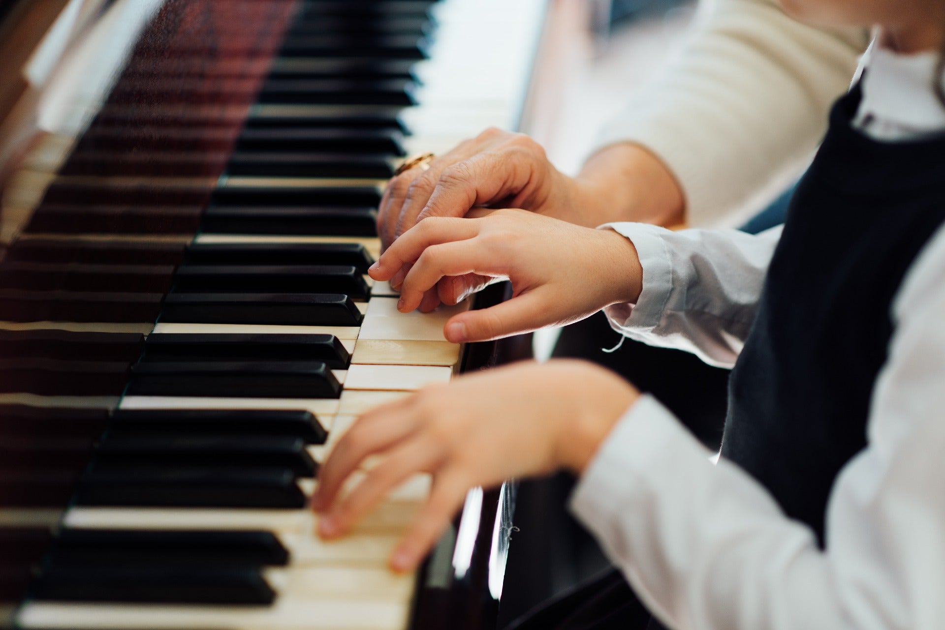 Hands playing an acoustic piano keyboard during technical piano service evaluation